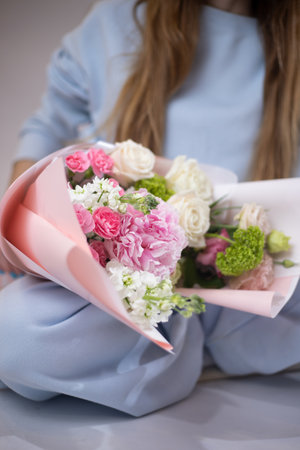 Woman with a delicate summer bouquet of flowers. The florist creates a red beautiful bouquet of mixed flowers. Flower shop. Fresh bouquet. Master classes and floristry courses. Flower delivery.の写真素材