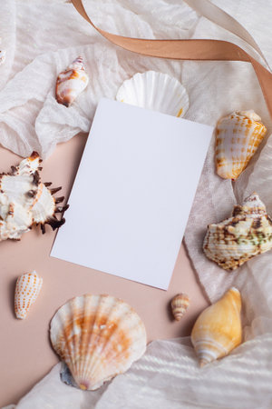 Mockup of a postcard with seashells on a pink background with fabric. Elegant composition with a blank white sheet for text. Vacation and travel conceptの写真素材