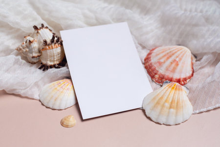 Mockup of a postcard with seashells on a pink background with fabric. Elegant composition with a blank white sheet for text. Vacation and travel conceptの写真素材