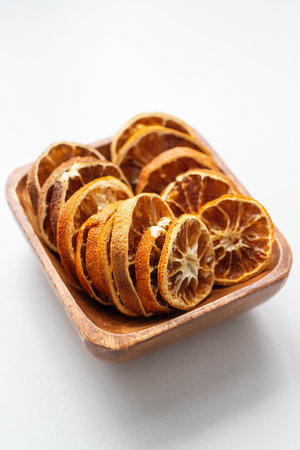 Dried orange slices in a wooden bowl on a white background. Dried fruits for mulled wine and New Years decor. Citrus fruits for tea and aromatherapyの写真素材
