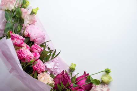 Bouquet of pink flowers on a white table, top view. Beautiful floral composition of roses, peonies, eustoma and hydrangea, in pink packaging. Wedding bouquetの写真素材