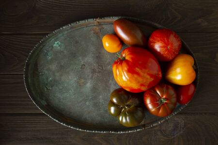 Ugly raf, kumato, heirloom  tomatoes on brass tray with copy space, homegrown and  fresh gathered.の写真素材