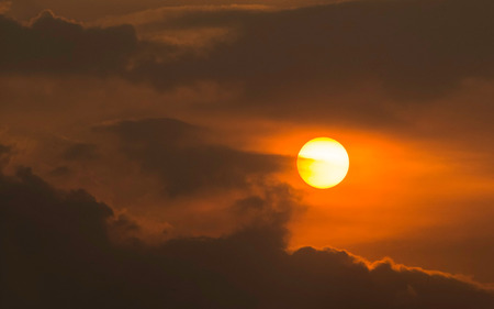 Scenery of sun in perfectly rounded shape. Accompanied by a cloud formation around the sun. Captured at sunsetの写真素材