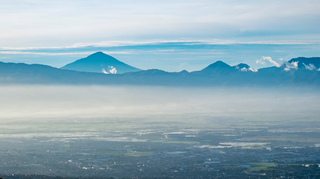 Aerial view of city and mountain when illuminated by sunlight in faraway, captured  from Moko Hills when weather is sunny, Bandung, Indonesiaの写真素材