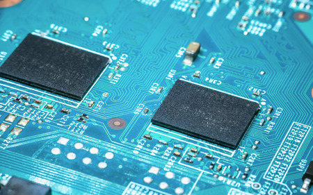 Photo of Two black microchip in blue printed circuit board (PCB), showing beautiful pattern of...