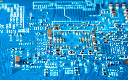 Photo of  electric component in electronic device, contain small resistor in beautiful rectangle formation, small capacitor, microchip and capacitor on blue printed circuit board. Look like a small city, captured using focus stacking methodの写真素材
