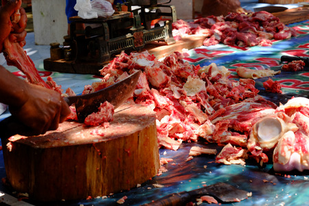 Pile of chunks raw cow's meat and bone, and also people who chopping meat using  machete or chopping kniveのeditorial素材