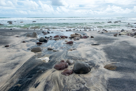 Formation of little rocks and black beach sand at the beach after swept away by the waves. Captured on Menganti Beach, Kebumen, Indonesiaの写真素材