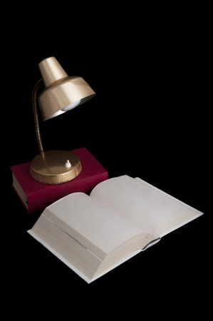 Desk lamp and books isolated on black backgroundの写真素材