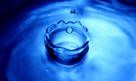 detail of water drop falling into water surface