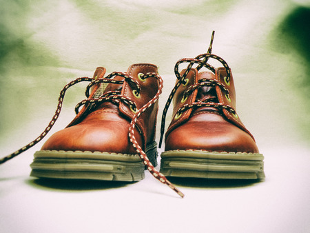 Red baby or kid shoes on white old paper background. Retro look.の写真素材