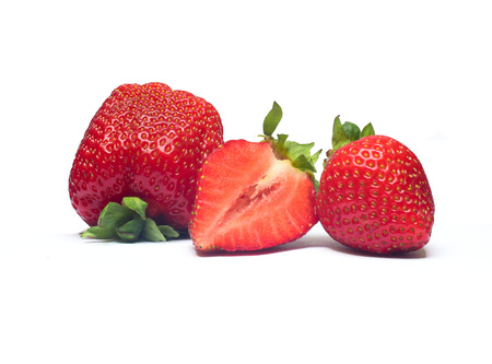 Three juicy and organic strawberries with strawberry leaf on white background.の写真素材