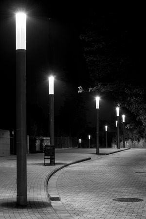 Night photo of row of streetlights in a curved and cobbled Streetの写真素材