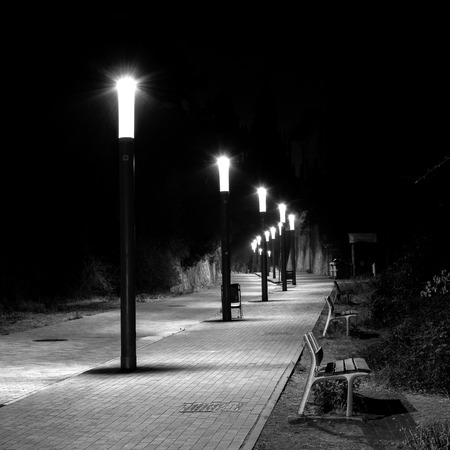 Night photo of row of streetlights in a curved and cobbled Streetの写真素材
