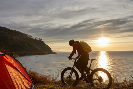Tourist rides a bike with wide wheels along the shore of Lake Baikal.の写真素材