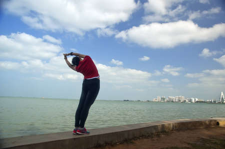 A girl facing the sea to practice yogaの写真素材