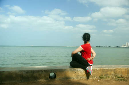 A girl facing the sea to practice yogaの写真素材