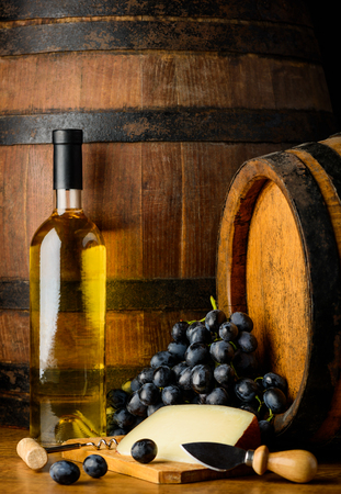 White wine in bottle with dark grapes and chese with wooden backgroundの写真素材