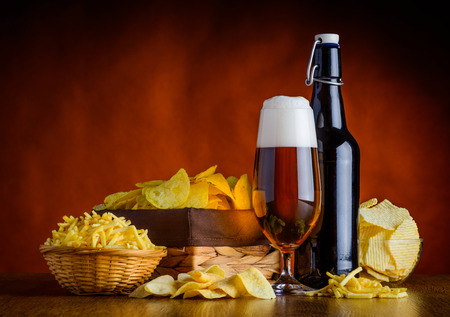 Glass and Bottle Beer with junk-food, potato-chips in still lifeの写真素材