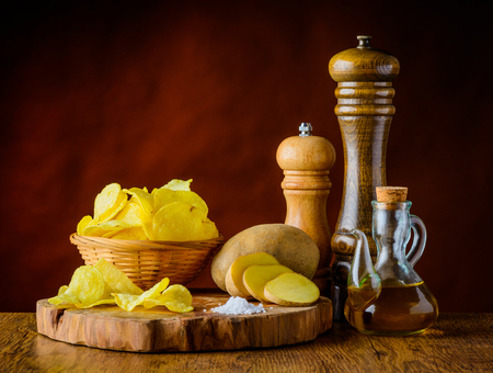 Potato Chips and ingredients in still life on wooden chopping boardの写真素材