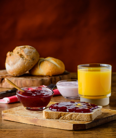 Fruit Jam spread on bread and glass of orange juiceの写真素材