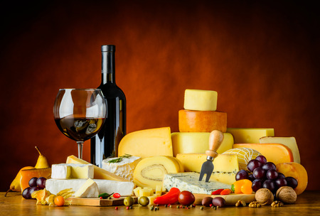 Red wine in glass and bottle with cheese and food in still lifeの写真素材