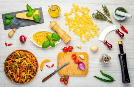 Penne, Conchiglie Rigate and colored Fusilli and cooking ingredients with Parmesan Cheese. Italian Cuisine Foodの写真素材