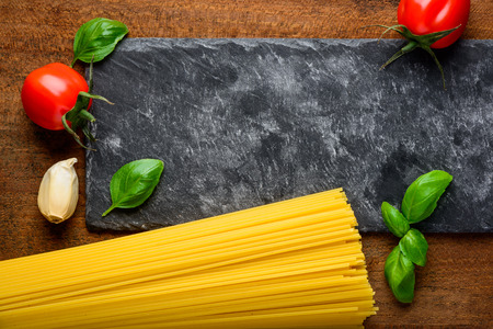 Yellow spaghetti bundle and italian or mediteranean cuisine food with cooking ingredients and copy spaceの写真素材