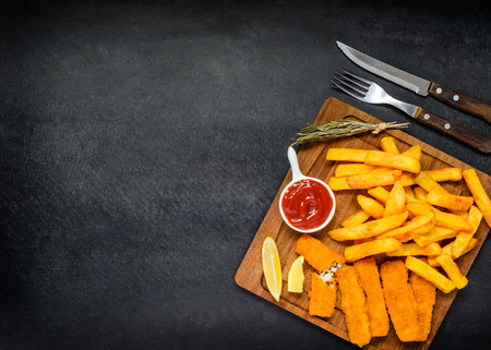 Copy Space Area with Fast food French Fries and Fish Fingers on Dark Backgroundの写真素材
