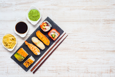 Japanese Cuisine Food with Soy Sauce and Wasabi. Sushi rolls and Sashimi on Dark Plate with Copsticks on Copy Space Areaの写真素材