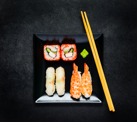 Sushi with Surimi and Caviar and Sashimi with Wasabi on Black Plate with Chopsticksの写真素材