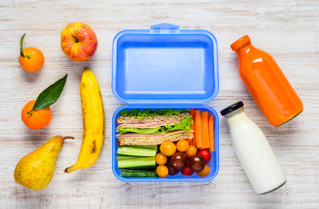 Blue Lunch Box with Sandwiches, Vegetables, Fruits and a Bottle of Milk in Top Viewの写真素材