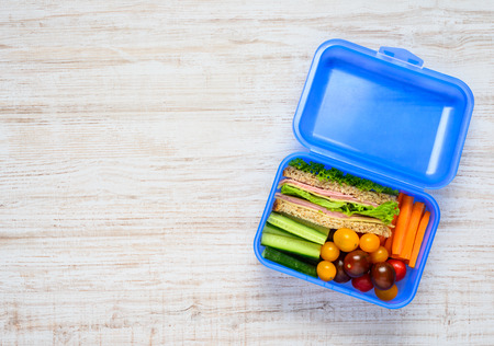 Top View of Blue Lunch Box with Food inside, Sandwich and Vegetablesの写真素材
