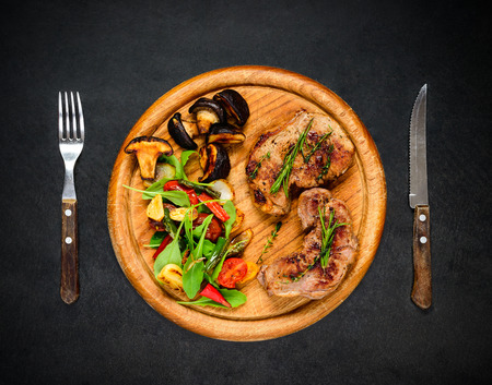 Top View of Grilled Steak Meat with Mushrooms and Vegetables on Wooden Boardの写真素材
