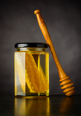 Full Glass Jar with Honey and Comb. Wooden spoon dipper.の写真素材