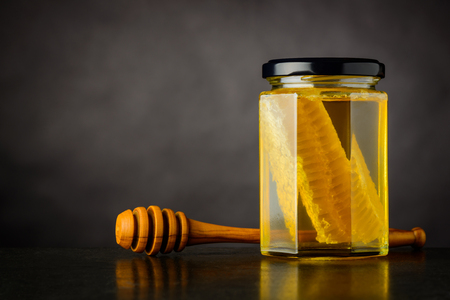 Copy Space Area with Glass Honey Jar and Dipper on Dark Backgroundの写真素材