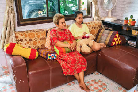 Asian family of mother daughter sitting on sofa talking with each other Thailandの写真素材