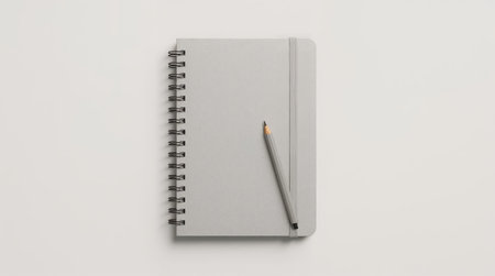 simple gray spiral notebook with pencil on white background representing minimal stationery design productivity and clean creative workspace conceptの素材