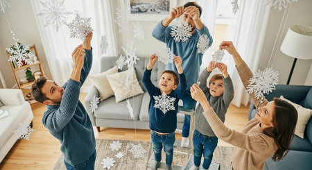 A family arranges paper snowflake decorations in a bright living room. Warm natural light creates a cozy, festive atmosphere suitable for seasonal and lifestyle marketing.の素材
