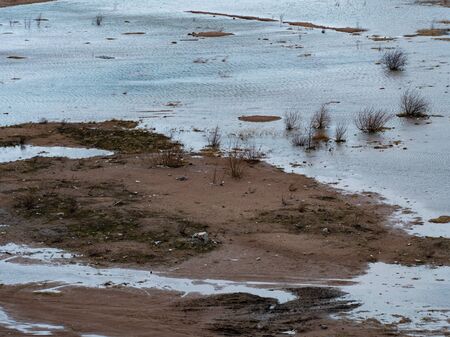 Graphic resources background image of the tread prints of a car on a clay coast of a reservoir....