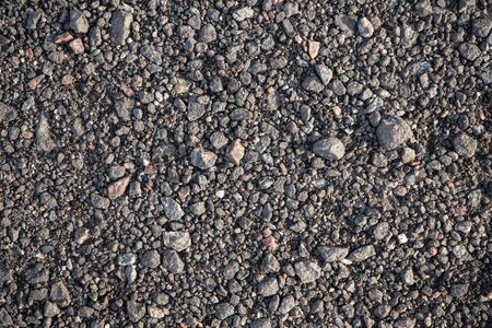 Background image of the surface covered with small gravel on the ground. Wallpaper. Substrate for text. Detailed texture of fine pebbles on the ground. The surface of the hiking trail. Top view.の写真素材