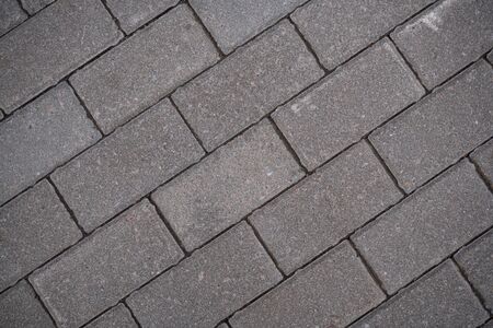 Background image of the surface of the sidewalk. Wallpaper. Substrate for text. Detailed texture of a pedestrian walkway with paving tiles. Paving slabs in the exterior. Top view.の写真素材