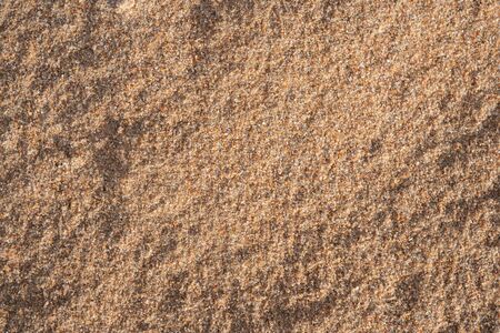 Background image of the surface of a sandy beach. Wallpaper. Substrate for text. Detailed sand texture. Sand on the seashore. Top view.の写真素材