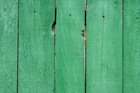Background image of a wooden fence. Texture of painted wood. Wooden boards. Old fence painted with green paint. Text space. Wallpaper. Texture for exterior and interior. Wood material for constructionの写真素材