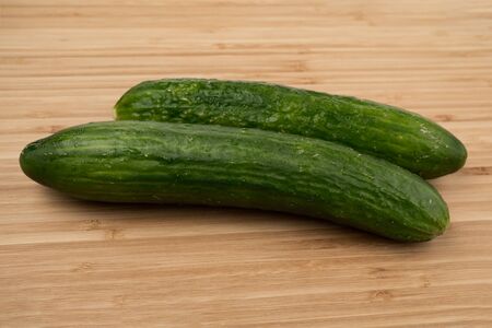 Cucumber on a wooden background. Wooden plank. Harvest fresh cucumbers. Ripe vegetable. Wood texture. Green smooth skin. A slice of cucumber. Vegetable diet. Proper nutrition. Ingredient for the saladの写真素材
