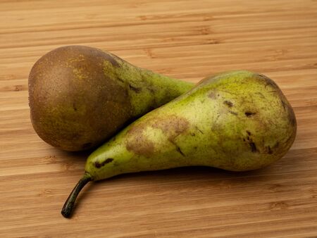 Pear on a wooden background. Wooden plank. Harvest fresh pears. Ripe vegetable. Wood texture. A slice of pear. Fruit diet. Proper nutrition. Tasty fruit. Soft shadows. Pear in the cut.の写真素材