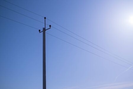 Minimalistic background image of power lines against a blue skyの写真素材