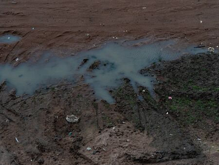 Graphic resources background image of the tread prints of a car on a clay coast of a reservoir. Flooded wasteland. Dirt on the banks of a spilled puddle.の写真素材