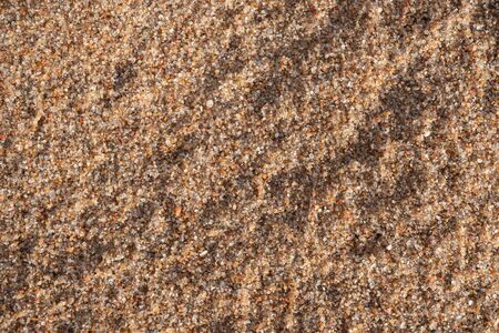 Background image of the surface of a sandy beach. Wallpaper. Substrate for text. Detailed sand texture. Sand on the seashore. Top view.の写真素材