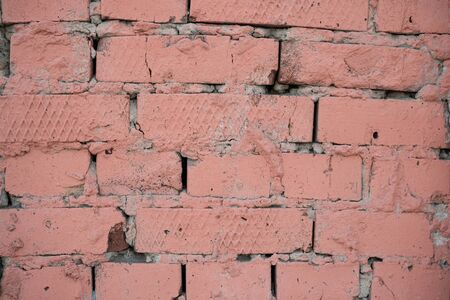 Background image of a painted brick wall. Sloppy brickwork. Detail brickwork texture. Texture for the interior. A wallpaper for the desktop. Text space. Painted in pink. Brick in construction.の写真素材